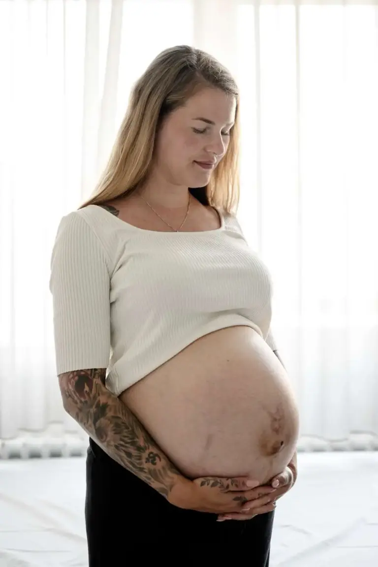 gravid kigger ned på sin højgravide mave