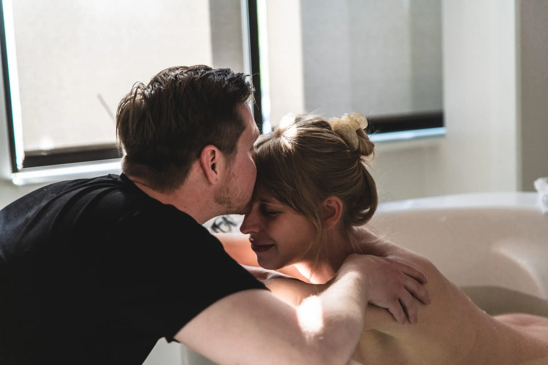 Gravid kvinde i badekar på fødestue med partner